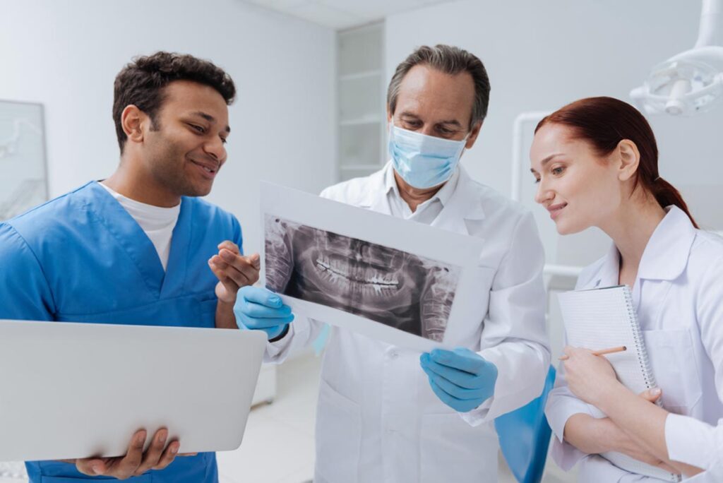 dentist looking at X-ray with dental students demonstrating reasons to join a dental student training program