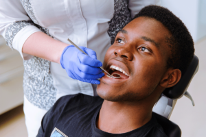 Dentist checking young man's mouth after tooth extraction and explaining what to know about recovery after a tooth extraction