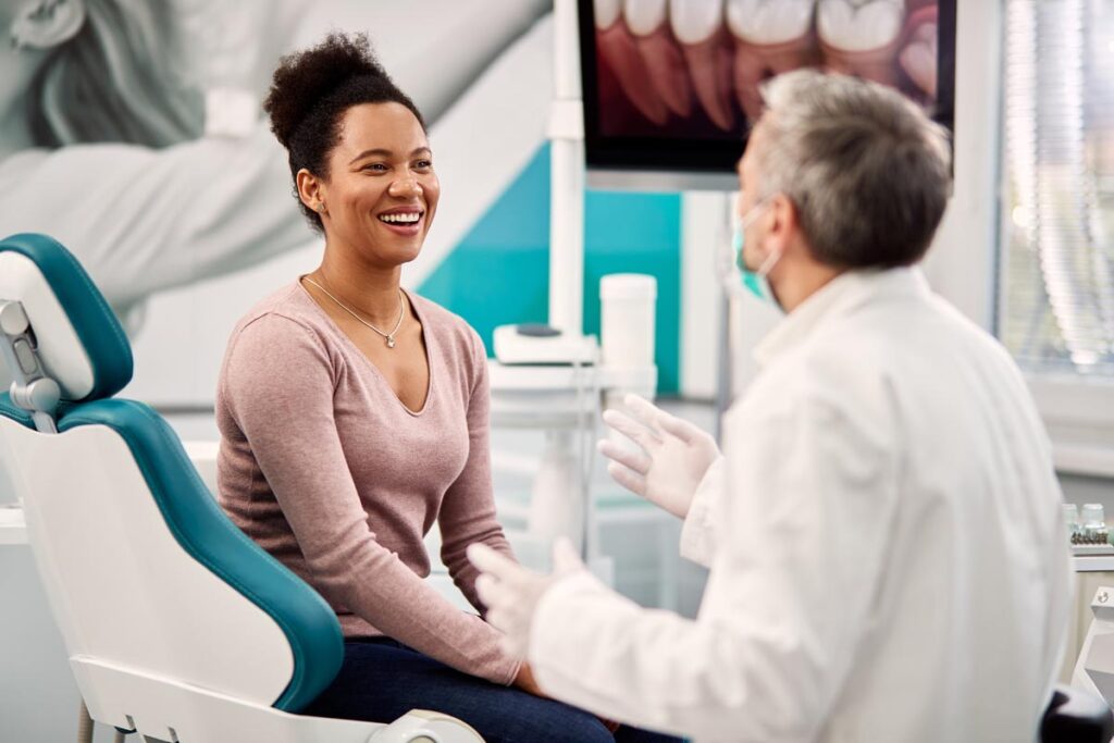Smiling patient and prosthodontist discussing why dental health is so important