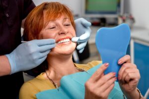 person smiling in dental chair learning about snap-on dentures pros and cons